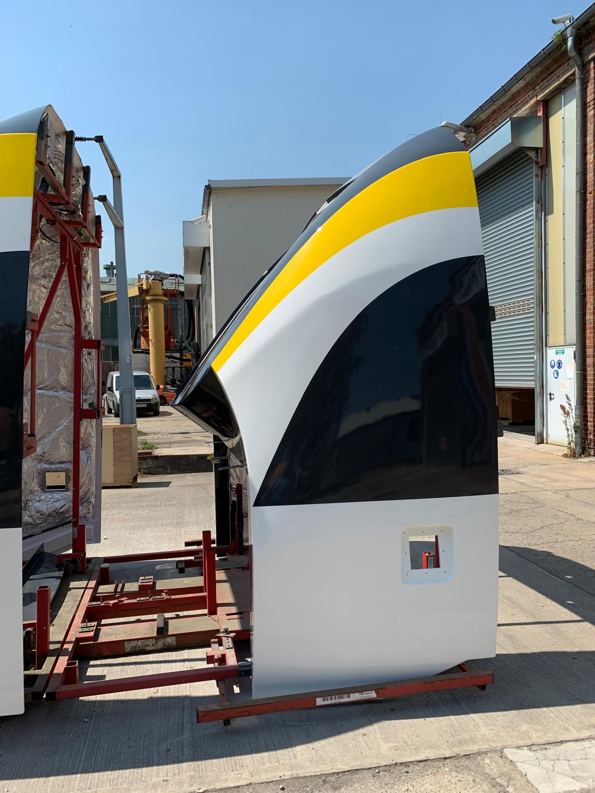 Fahrzeugfront mit gelb-schwarz-weißem Mehrfarbdesign auf Transportgestell im Werkhof